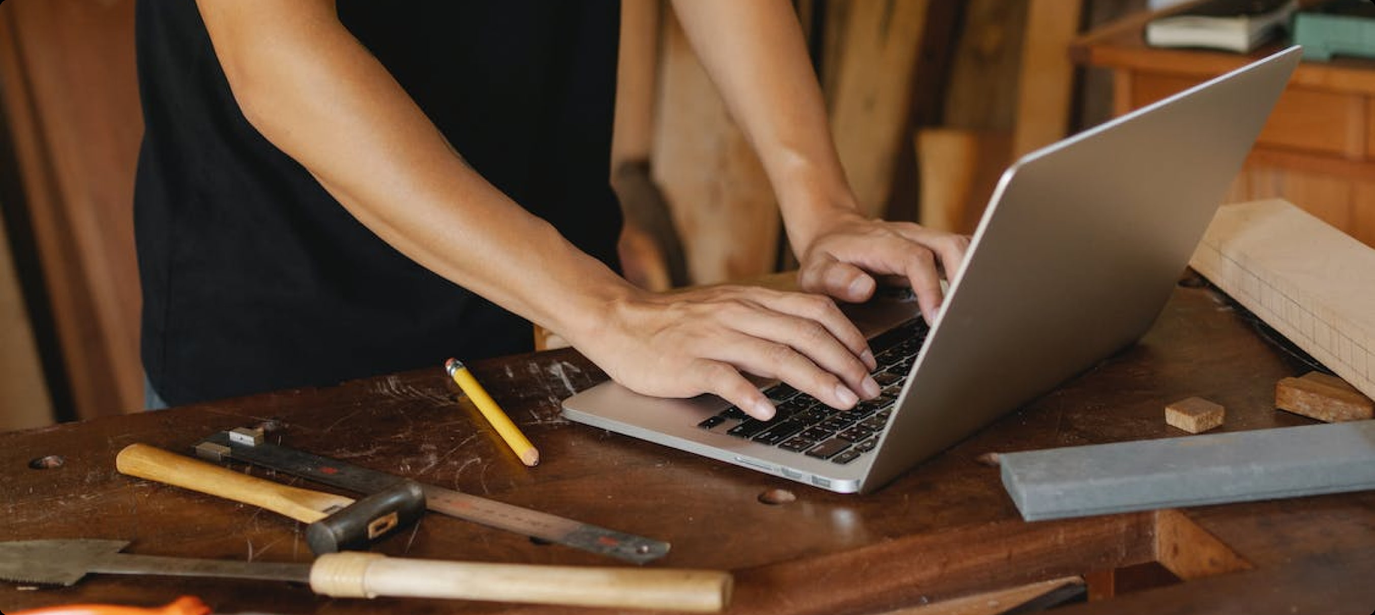 a professional craftsman in his workshop using his laptop